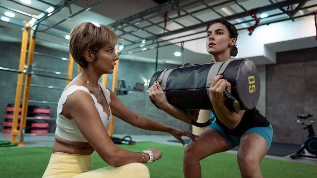 A man and a woman doing squats in a gym